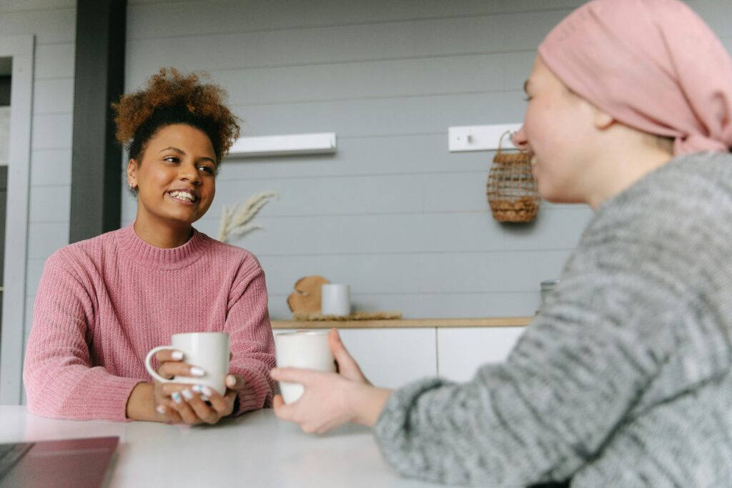 Two people talking while holding mugs.