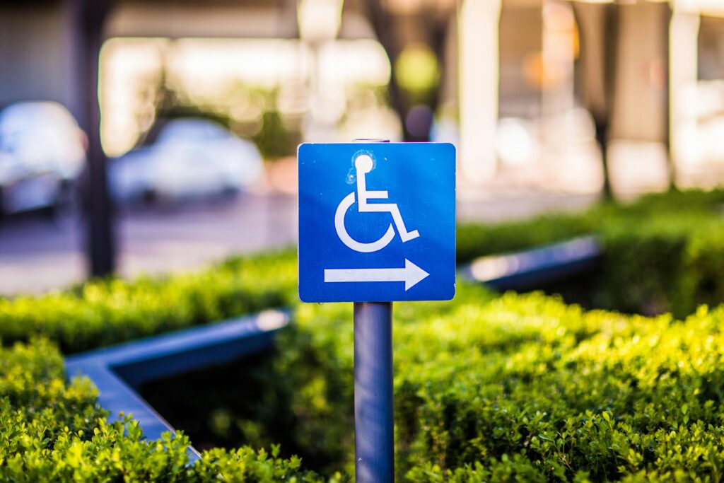 A wheelchair accessibility sign erected from the bushes