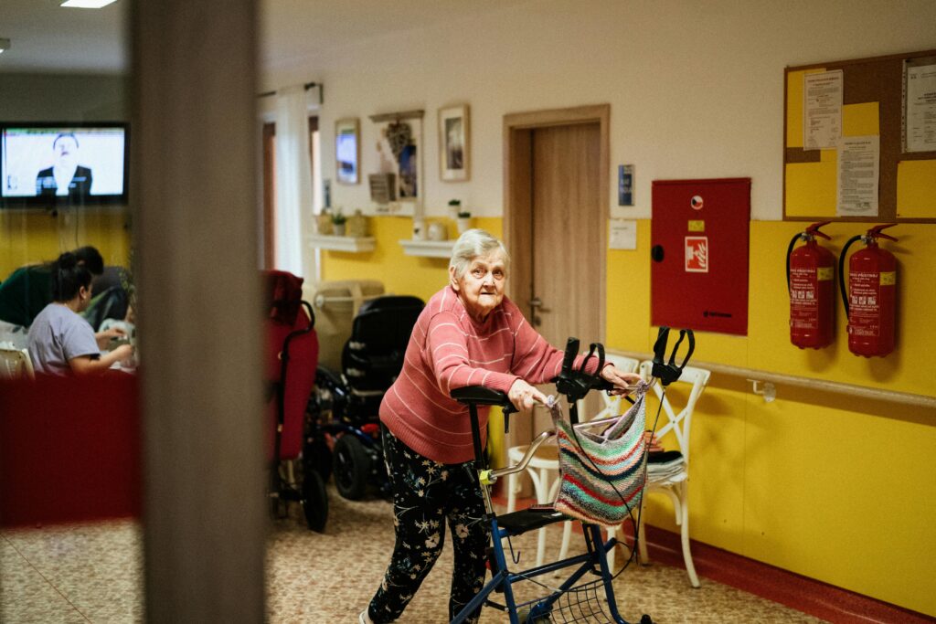 An elderly person walking through a hospital using a walker