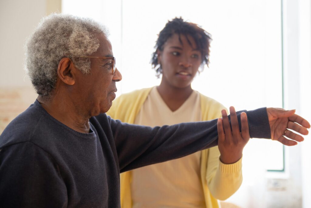 A person lifting up an elderly person's arm