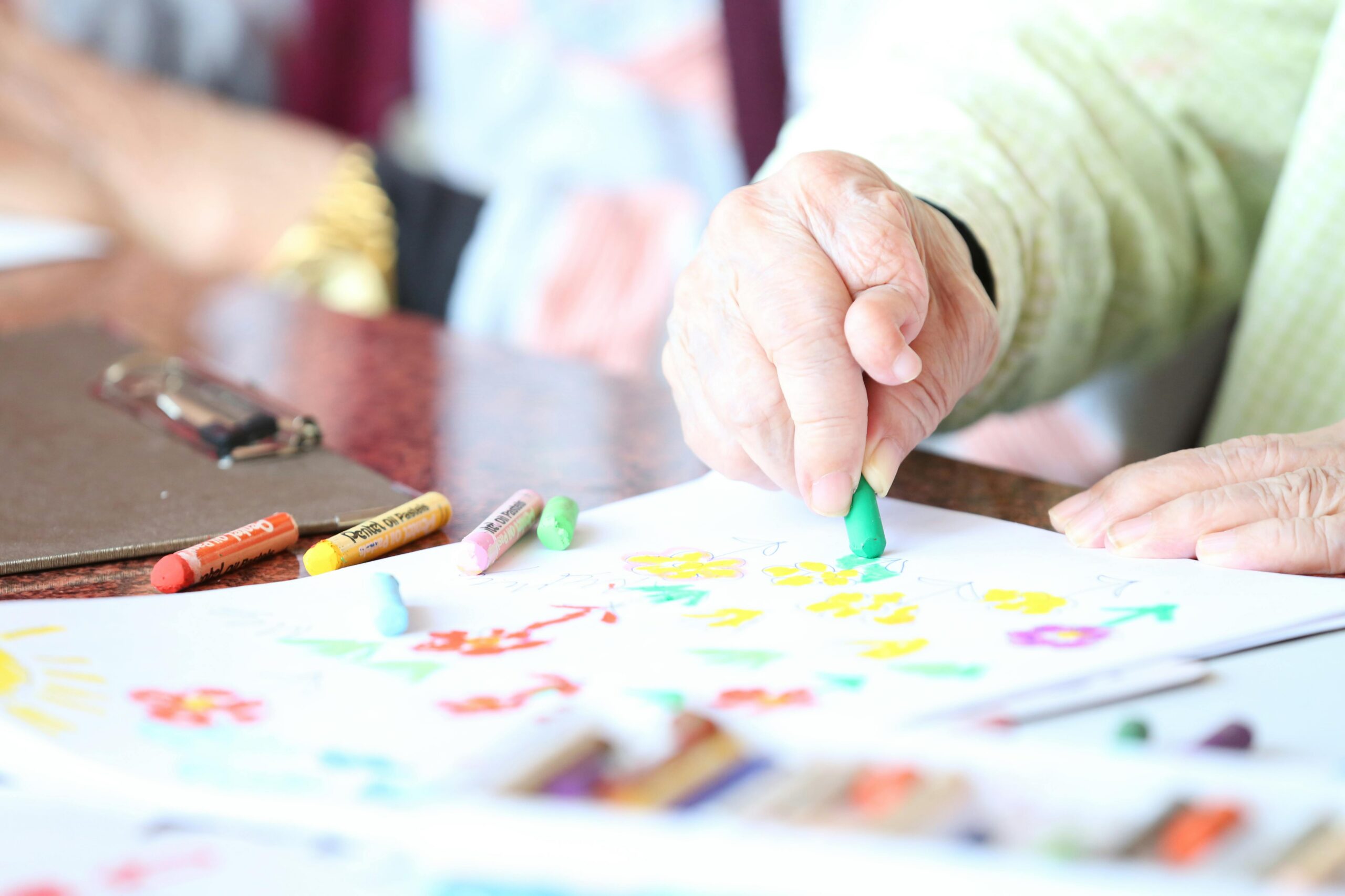 An older person coloring a book with a green crayon